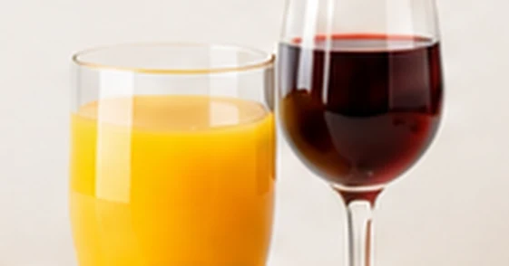 Een glas sinaasappelsap en een glas rode wijn